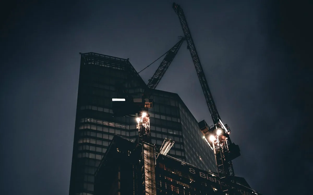 Fenced construction site under temporary lighting at night